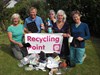 Photograph of a group of people with a pile of rubbish holding a Recycling Point poster