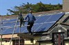 Photograph of a man installing photovoltaic panels on a roof