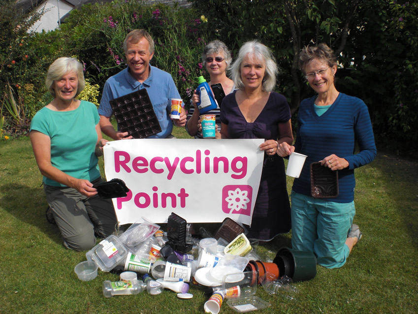 Photograph of a group of people with a pile of rubbish holding a Recycling Point poster